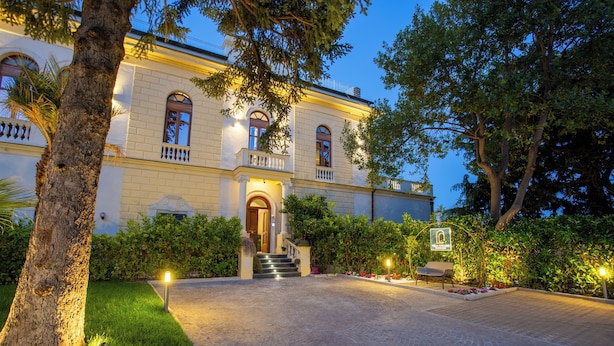 A historic building with a grand entrance, a well-maintained garden, and a paved driveway leading to the entrance. - Villa Cipriano - Relais di Charm (Naples)