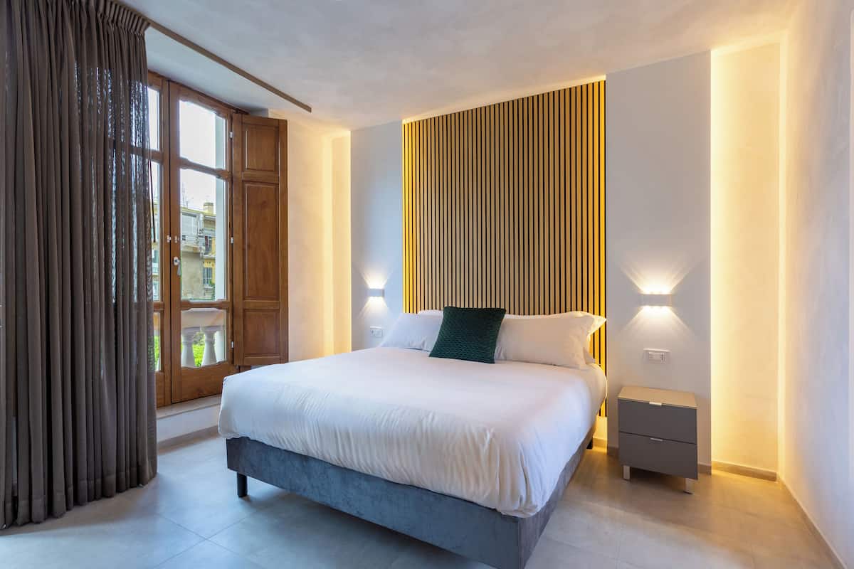Une chambre moderne avec un grand lit, un mur recouvert de panneaux en bois et deux lampes de chevet.
