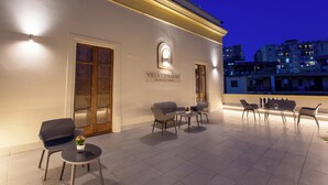 An outdoor seating area with modern chairs and a small table, a sign reading "Villa Cipriano," and a view of the cityscape in the background. - Villa Cipriano - Relais di Charm (Naples)