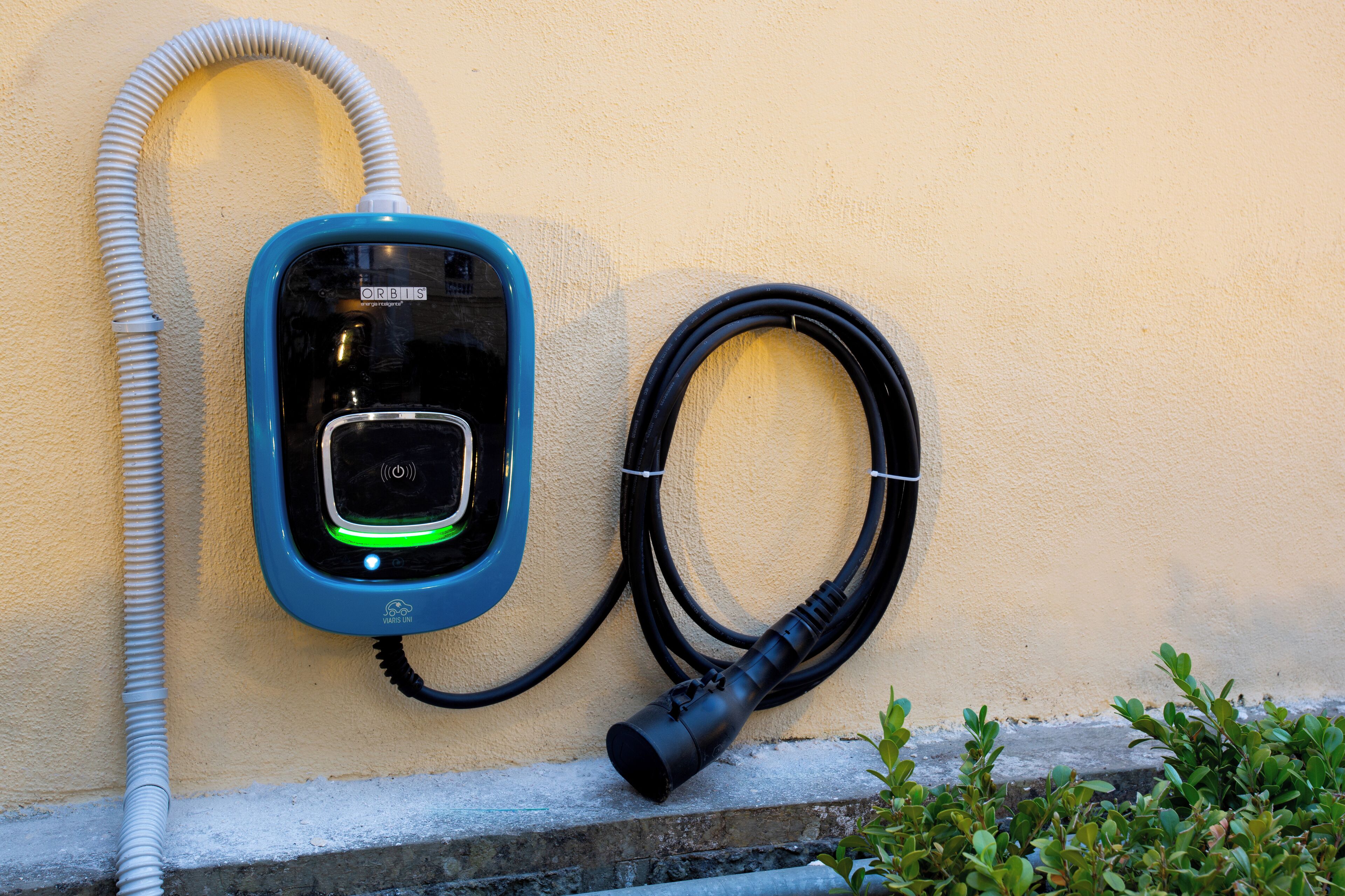 Stazione di ricarica per veicoli elettrici fissata al muro, con cavo e spina.