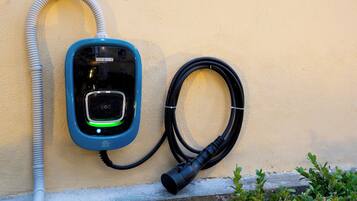 Stazione di ricarica per veicoli elettrici fissata al muro, con cavo e spina.
