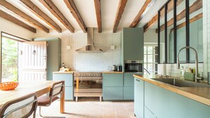 A kitchen with wooden beams, a stove, and a sink. - Beautiful Normand-style house with pool, 3 minutes from the beach (Auberville)