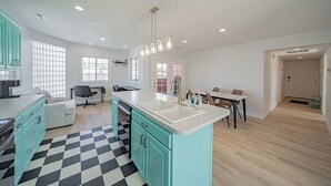 Een moderne keuken met een centraal eiland, een eetgedeelte met tafel en stoelen, en een woonruimte met een bank en salontafel.