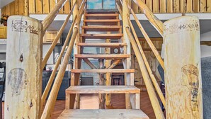Una scala in legno con una panca ai piedi, circondata da pali di legno intagliati.