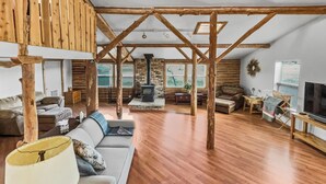 Un ampio soggiorno con soffitto in legno, camino in pietra e una grande finestra.