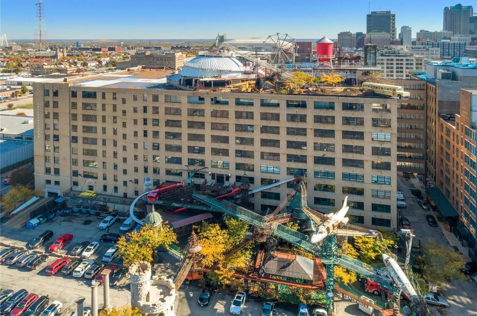 A multi-story hotel with a central courtyard, surrounded by parking and a nearby body of water.