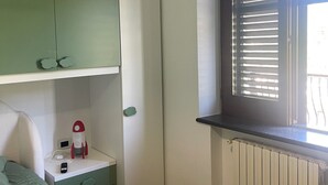 A bedroom with a bed, a green wardrobe, a small bedside table with a lamp, and a window with blinds. - Casa Viromar (Vico Equense)