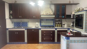 A kitchen with dark wooden cabinets, a tiled backsplash, a microwave, an oven, and a coffee maker. - Casa Viromar (Vico Equense)