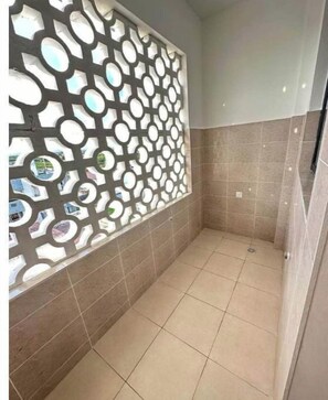 Shower area features a tiled floor and walls, with a decorative metal partition for partial visibility.