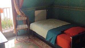 A small, cozy room with a single bed, a chair, and a window overlooking a balcony. - Belle Chambre Chaleureuse au Calme (Chennevières-sur-Marne)