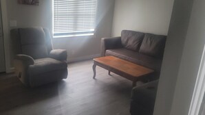 Una sala de estar con sofá, sillón y mesa de centro de madera.
