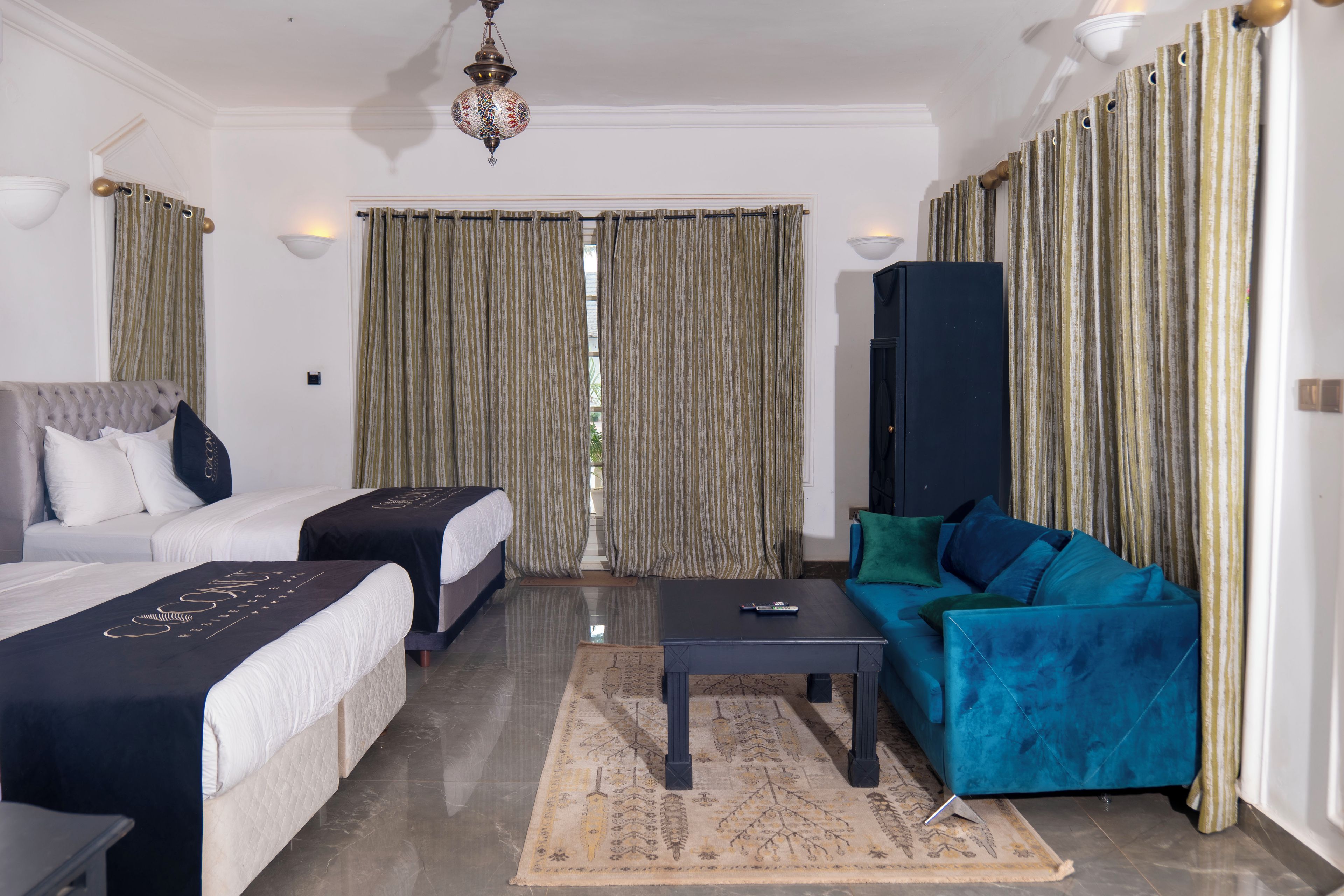 Una habitación de hotel con dos camas, un sofá, una mesa de centro y un mueble para televisión.