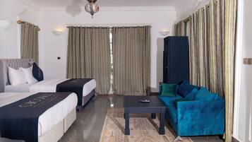Una habitación de hotel con dos camas, un sofá, una mesa de centro y un mueble para televisión.