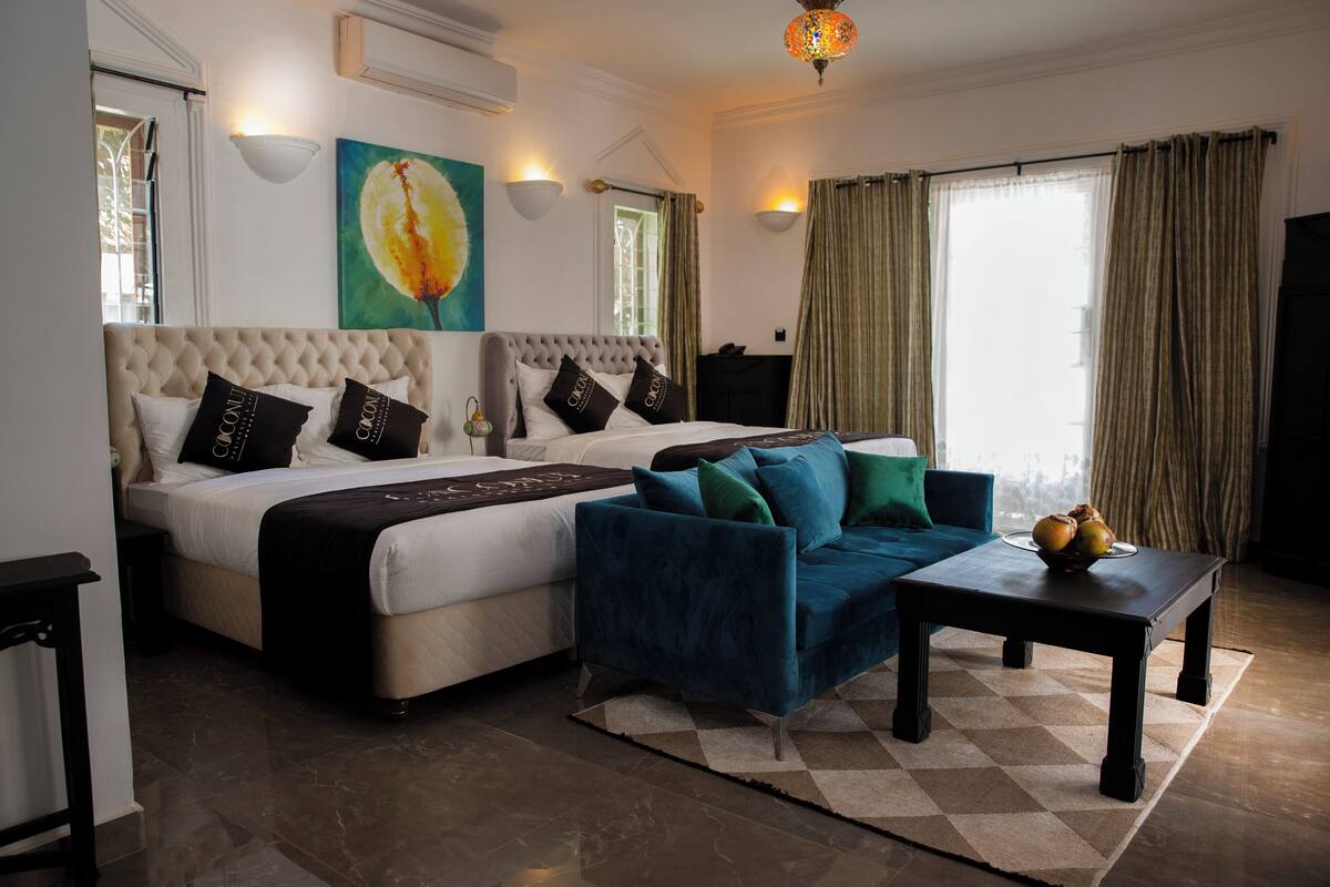 Quarto com cama grande, sofá, mesa de centro e um quadro na parede.