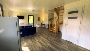 A spacious living area with a wooden staircase, a dining table with chairs, a blue sofa, and a white door. - MoreView Kopice directly on the Szczecin Lagoon (Stepnica)