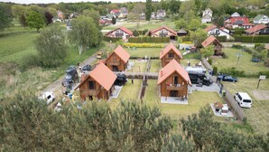 A cluster of wooden cabins with attached balconies, surrounded by a parking area and greenery. - MoreView Kopice directly on the Szczecin Lagoon (Stepnica)