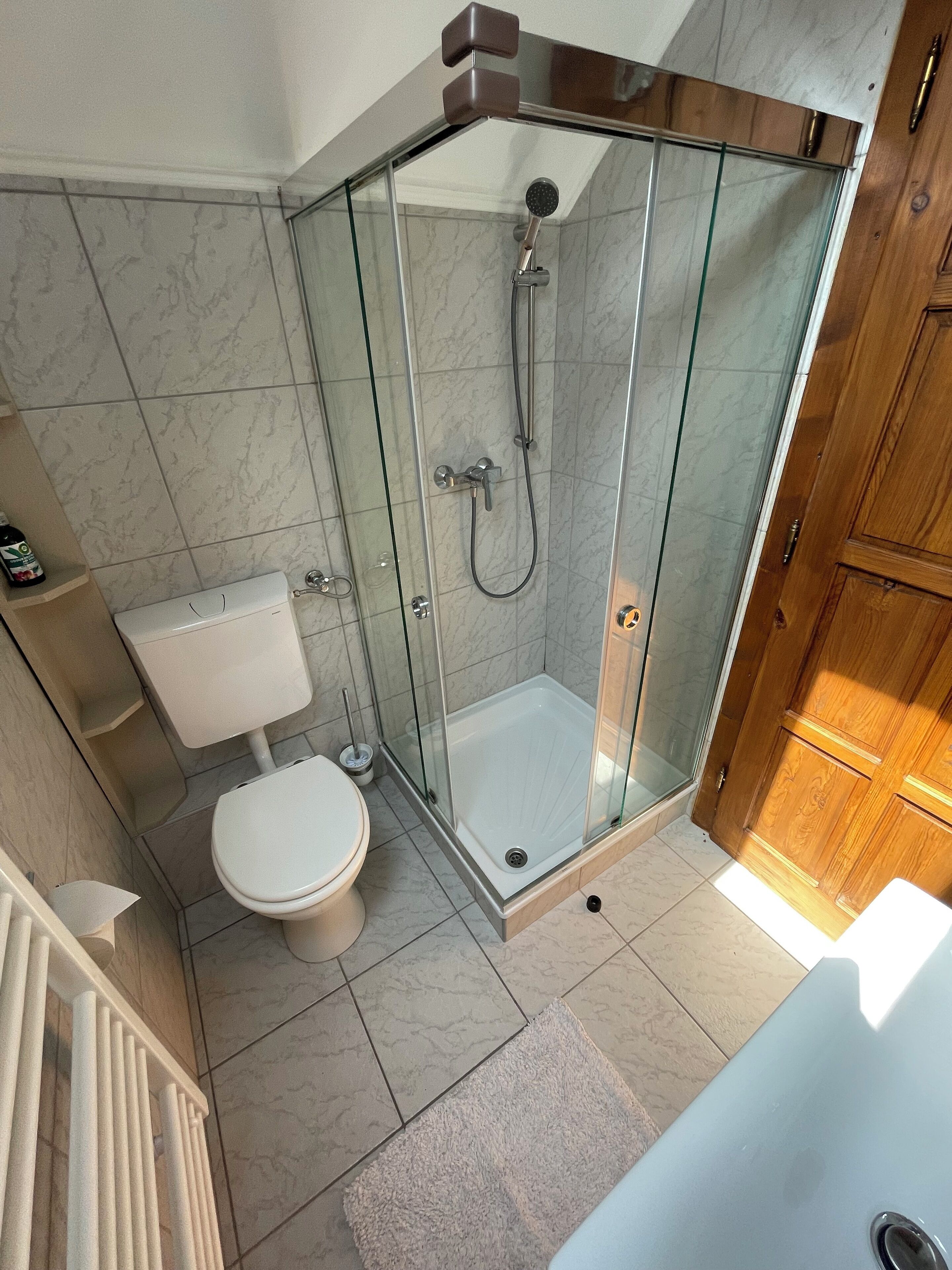 A modern bathroom with a glass-enclosed shower, a toilet, and a bathtub.