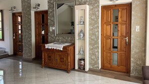 A hallway with wooden doors, a mirror, a cabinet, and a shelf with decorative items. - See Haus - Podmaniczky (Balatonfoldvar)