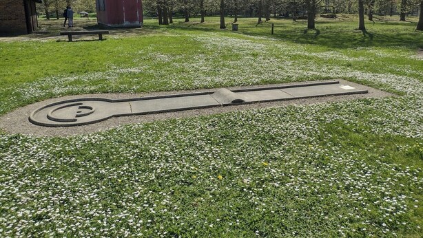 A park with a large, circular stone structure surrounded by grass and small white flowers. - Belle Chambre Lumineuse et Chaleureuse au Calme (Chennevières-sur-Marne)