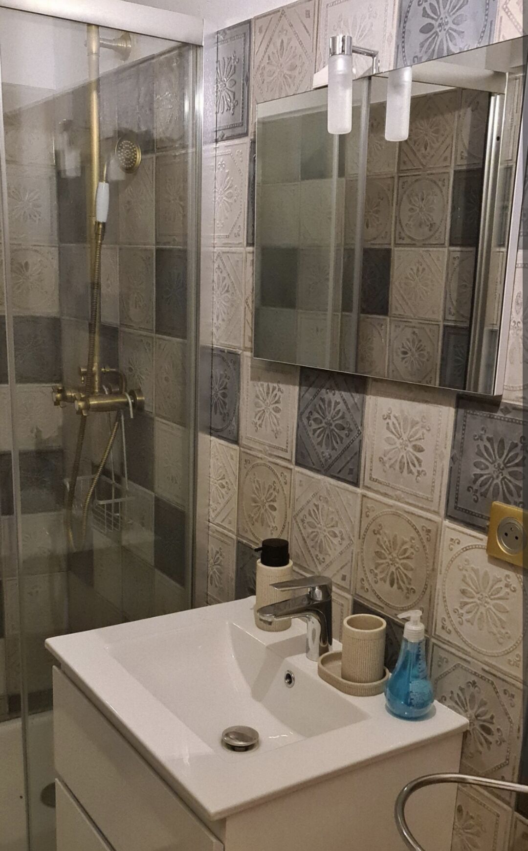Une salle de bain avec une douche à parois de verre, un lavabo blanc et un miroir au-dessus.