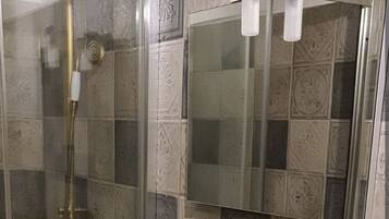 Une salle de bain avec une douche à parois de verre, un lavabo blanc et un miroir au-dessus.