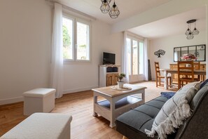 Un salon comprenant un canapé, une table basse, un téléviseur et un coin repas avec des chaises et une table.