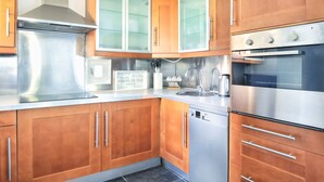 A modern kitchen with stainless steel appliances, wooden cabinets, and a dishwasher.