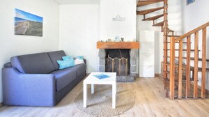 A living room with a grey sofa, a white coffee table, a fireplace, and a wooden staircase.