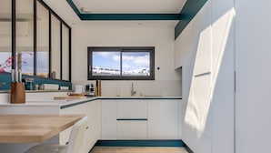 A modern kitchen with white cabinets, a wooden countertop, and a window with a view of buildings.