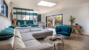 A modern living room with a sectional sofa, a round coffee table, and a teal armchair.