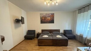 En moderne stue med en stor sofaseng, et fladskærms-tv på væggen og et billede over sofaen.