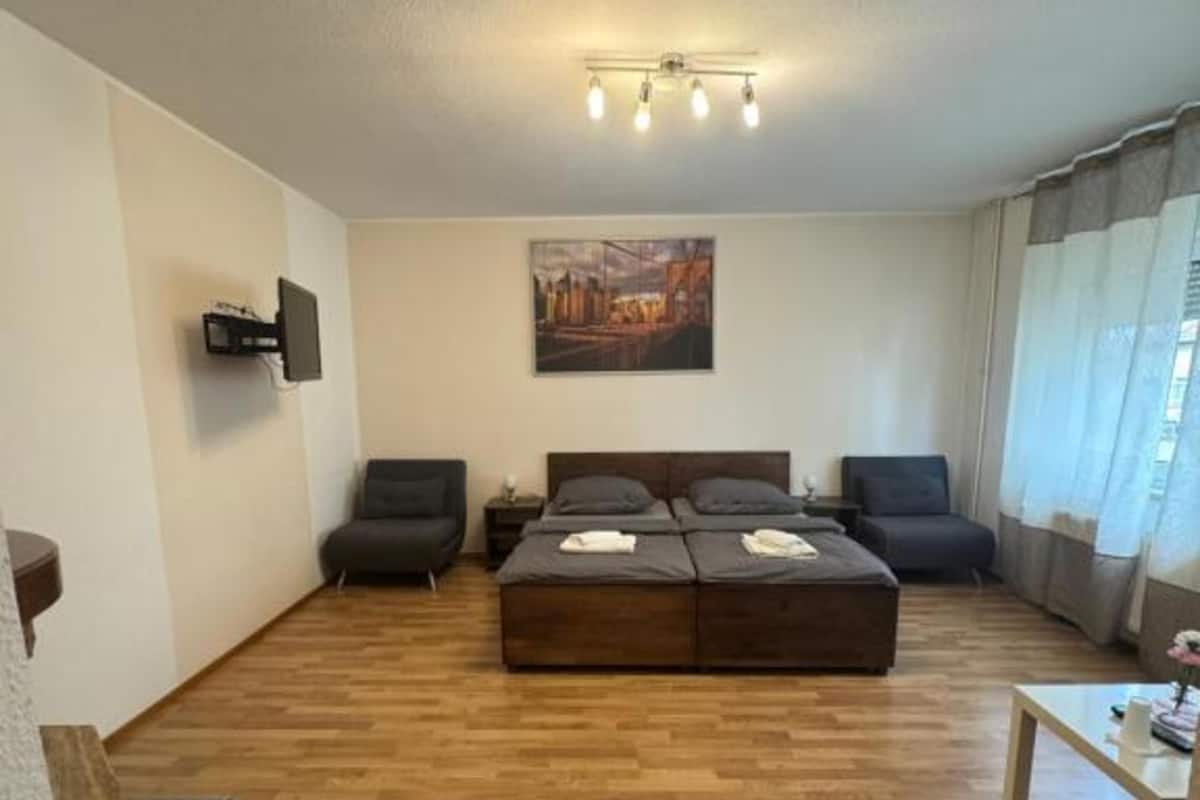 Uma sala de estar moderna com um amplo sofá modular, uma televisão de tela plana na parede e um quadro acima do sofá.