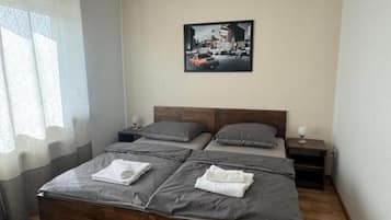 Een slaapkamer met een tweepersoonsbed, twee nachtkastjes, een raam met gordijnen en een schilderij aan de muur.