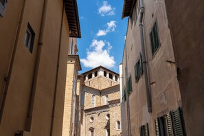 A narrow street with buildings on either side, a clear blue sky, and a prominent church tower in the background. - Appartamento con Camera Tripla in Palazzo Storico (Firenze)
