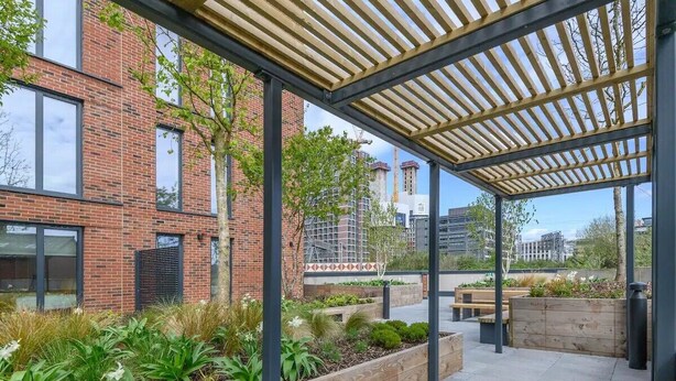 A covered outdoor area with wooden beams, brick buildings, and a garden with various plants. - City Centre Deluxe with amazing Garden Terrace - Pass the Keys (Leeds)