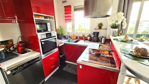 A compact kitchen with red cabinetry, a built-in oven, and a window providing natural light.