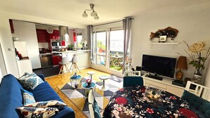 A modern living room with a sofa, a TV, and a dining area with a table and chairs.
