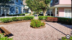 A paved walkway with a bench, surrounded by well-maintained hedges and a white picket fence. - Mom's Magical Retreat
"Close to the Magic, but away from the mayhem!" (Kissimmee)