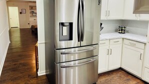 Un frigorifero in acciaio inox in una cucina con mobili bianchi e pavimento in legno.