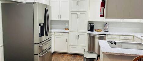 A modern kitchen with white cabinets, stainless steel appliances, a dishwasher, and a coffee maker.
