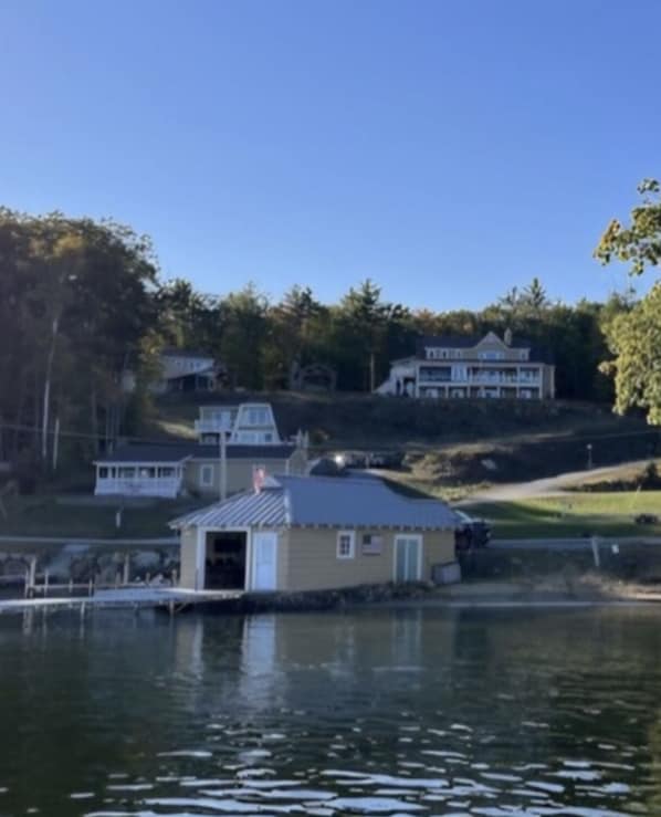 A lakeside property with a dock, a small cabin, and a larger house on a hill.