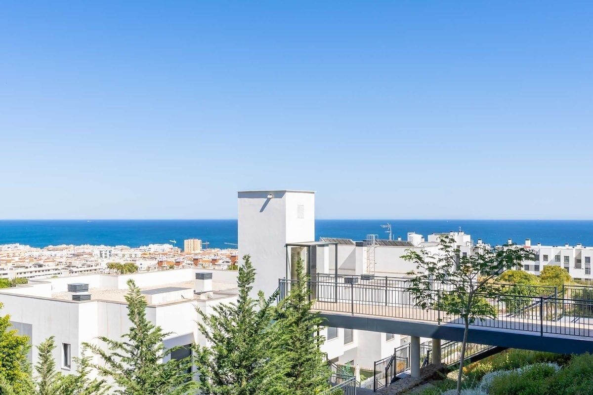 Un edificio moderno con una terraza en la azotea y vistas a la ciudad costera.