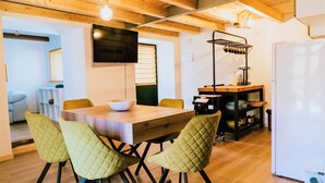 Une cuisine moderne avec une table en bois, des chaises vertes, un téléviseur et un four encastré.