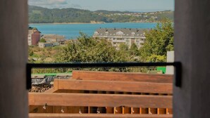 Une vue depuis un balcon donnant sur une zone côtière, avec des bâtiments et une étendue d’eau.