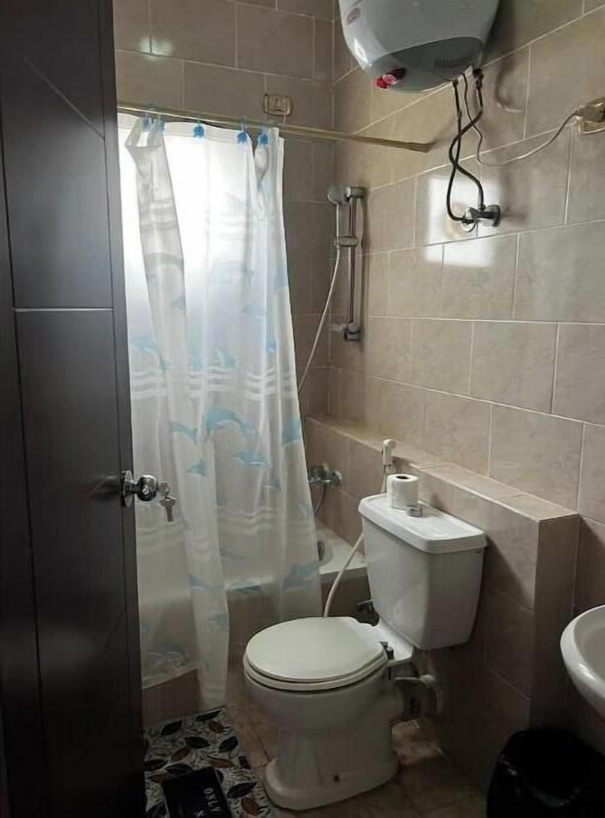 A small bathroom with a toilet, a shower, and a sink.