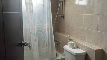 A small bathroom with a toilet, a shower, and a sink.