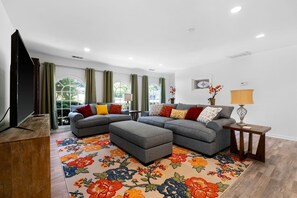 A modern living room with a sectional sofa, a flat-screen TV, and a floral area rug.