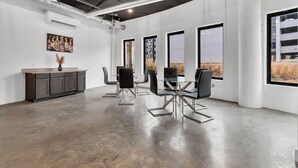 Een ruime vergaderzaal met een modern design, met een glazen tafel, zwarte stoelen en een donker houten kast.