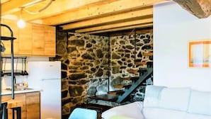 Une pièce chaleureuse avec une table à manger en bois, un canapé blanc et un mur en pierre.
