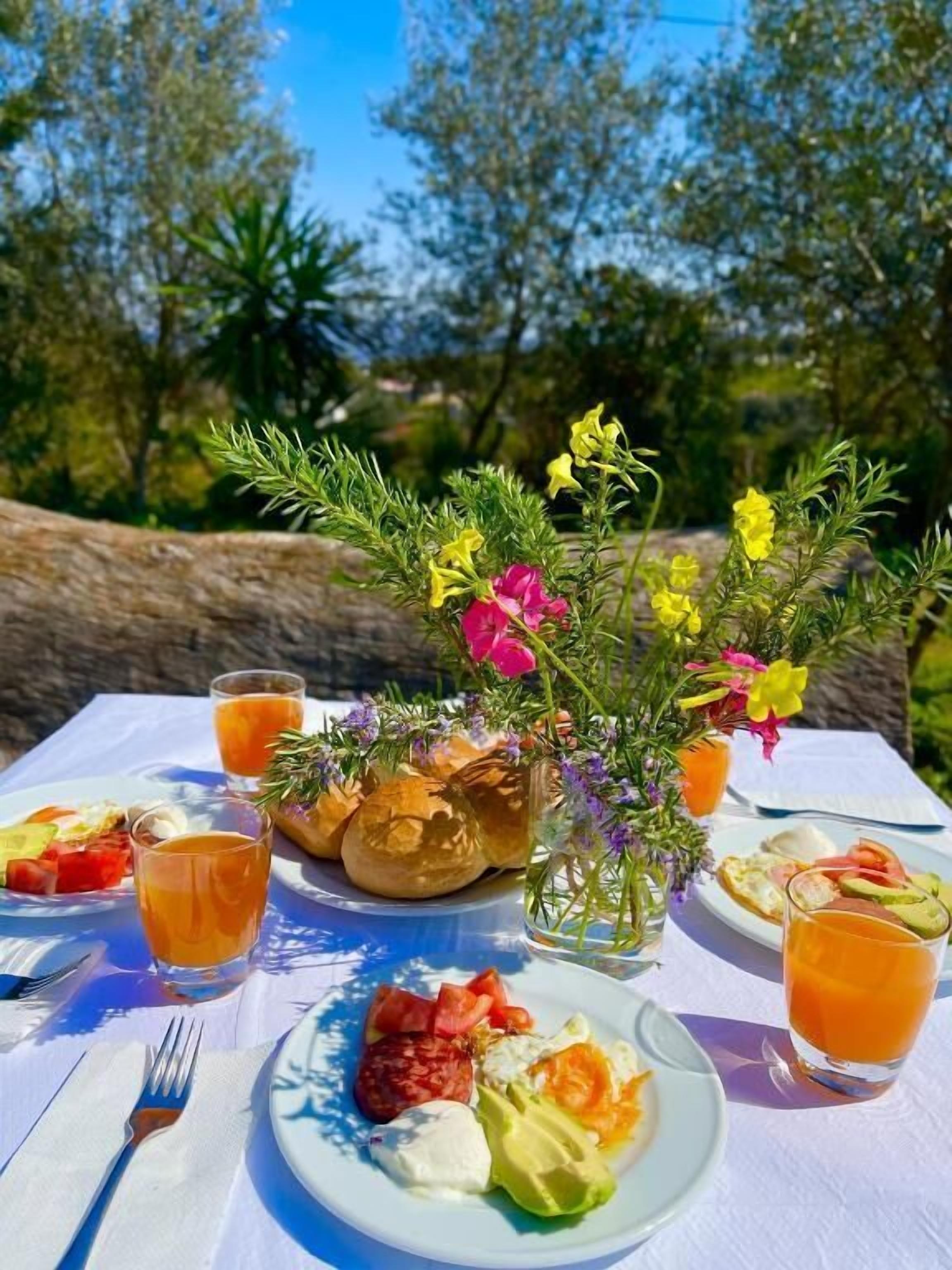 Une table dressée à l’extérieur, avec une variété de plats, de boissons et un arrangement floral en guise de centre de table.